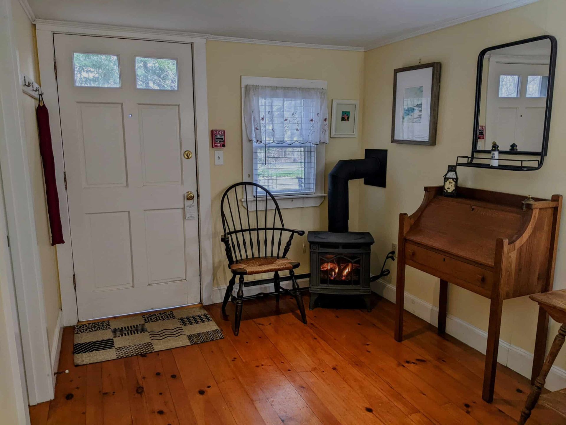 A living room with a wood stove , chair , desk and mirror.