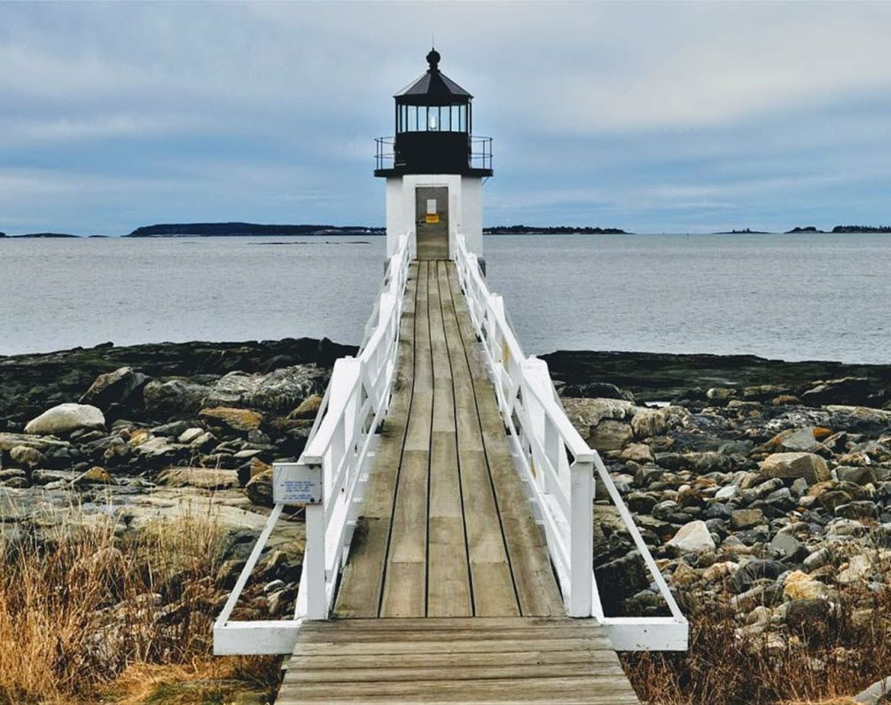 A wooden dock leads to a lighthouse overlooking the ocean