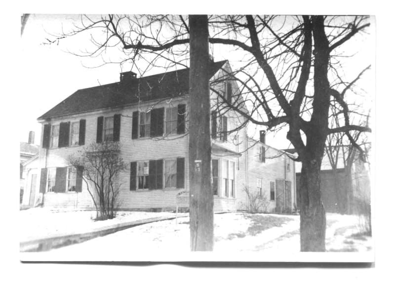 A black and white photo of a house with trees in front of it