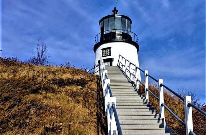 A lighthouse on top of a hill with stairs leading up to it.