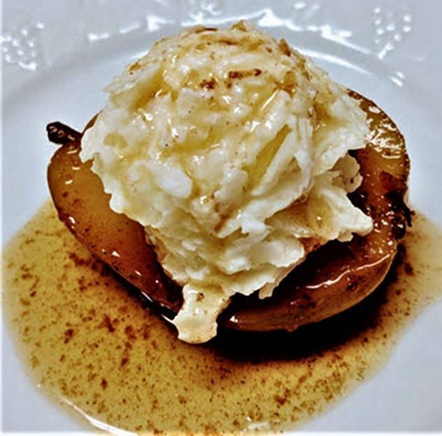 A white plate topped with a pear and whipped cream