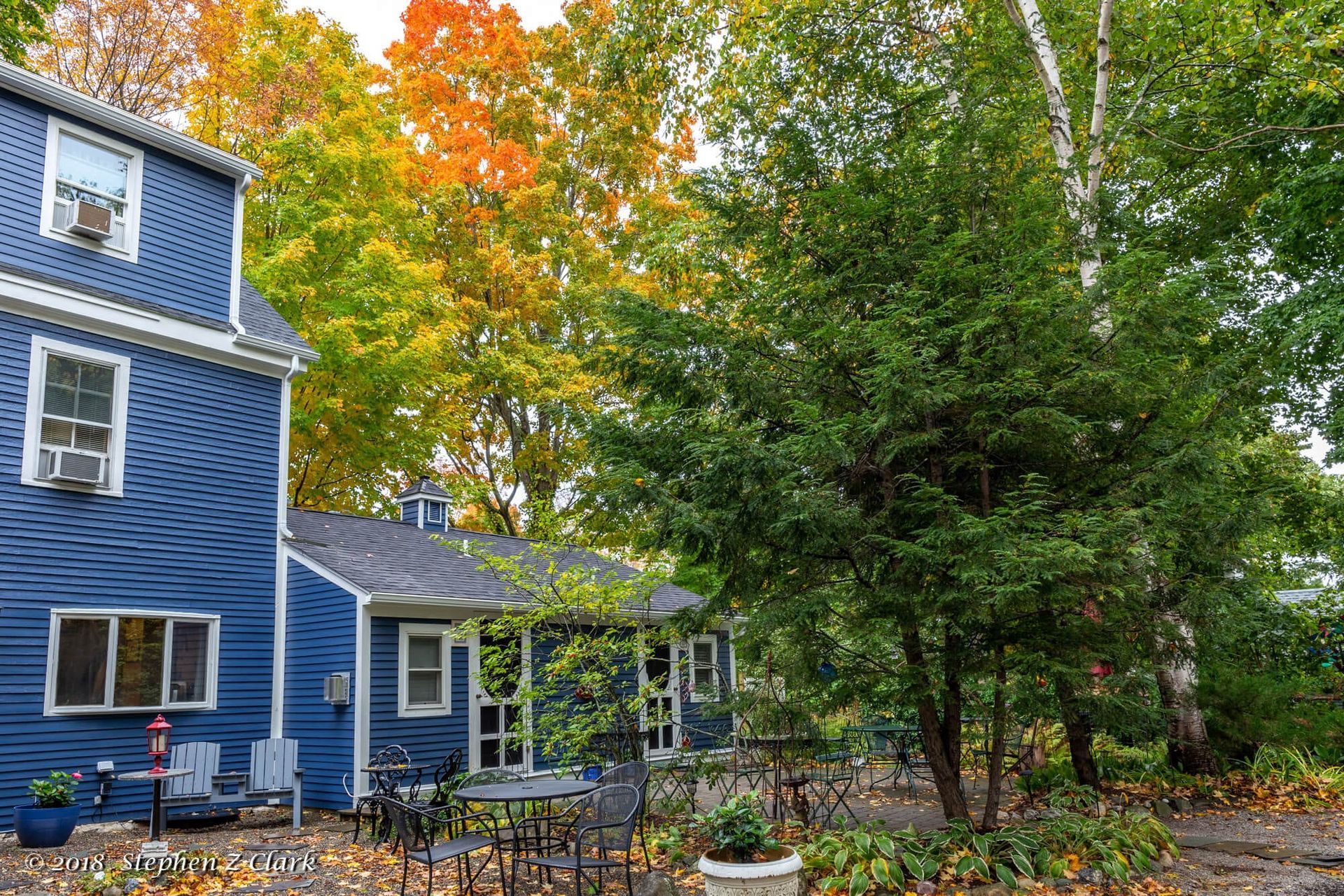 A blue house with a patio and trees in front of it.