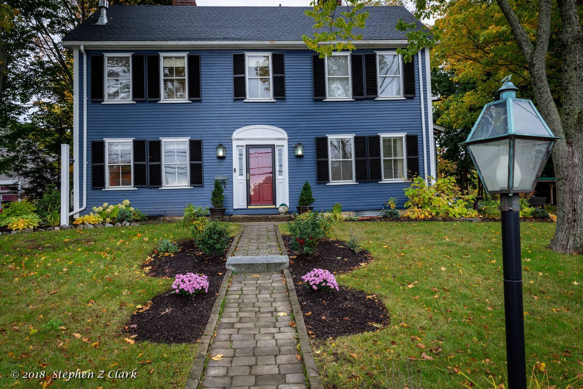 A blue house with black shutters and a red door