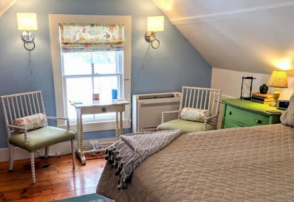 A bedroom with a bed , two chairs , a desk and a window.