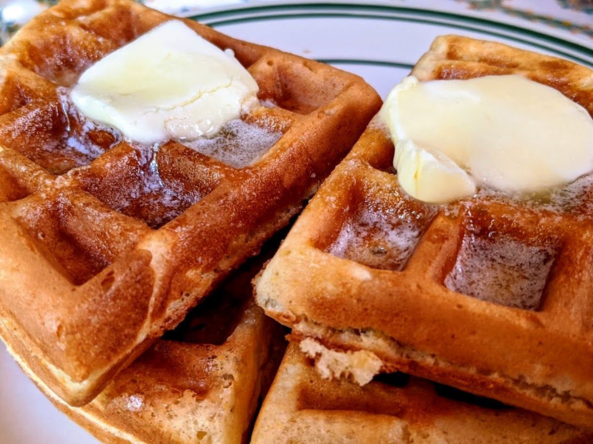 A close up of a plate of waffles with butter on top