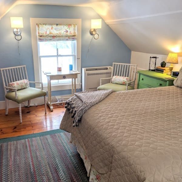 A bedroom with a bed and chairs and a window