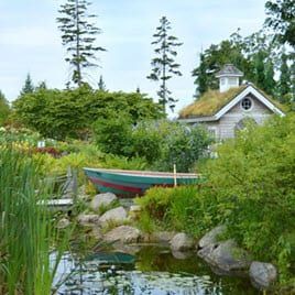 A boat is sitting in a pond in front of a house with a green roof.