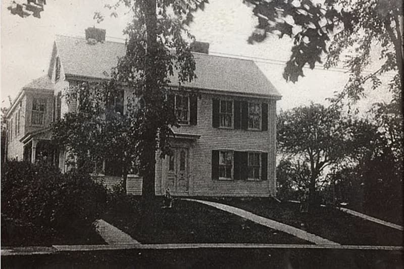 A black and white photo of a house with trees in front of it