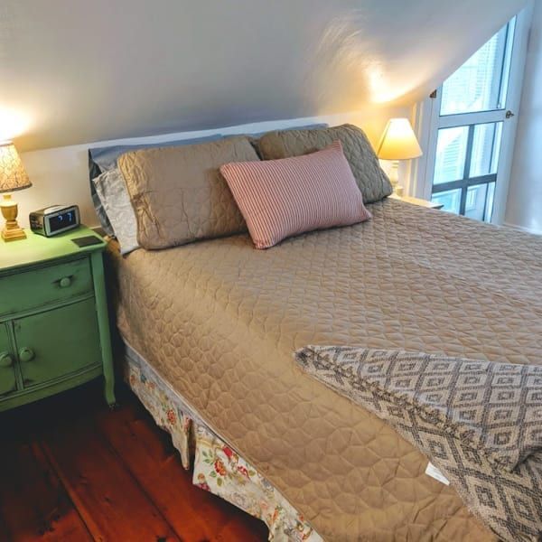 A bedroom with a bed and a green nightstand
