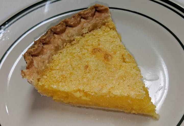 A slice of lemon pie is on a white plate.