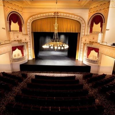An auditorium with a stage and a chandelier hanging from the ceiling