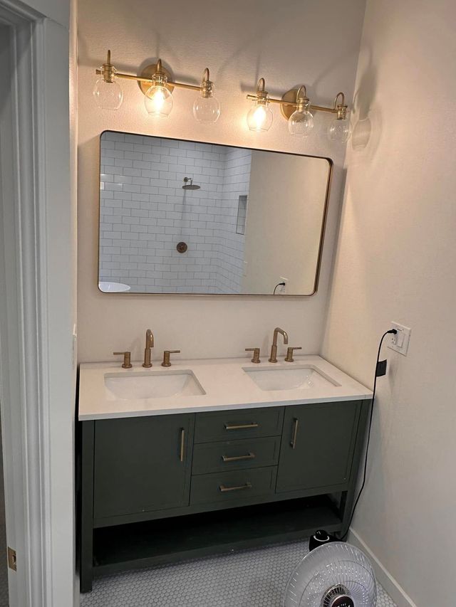 White bathroom with oval mirror and gold fixtures