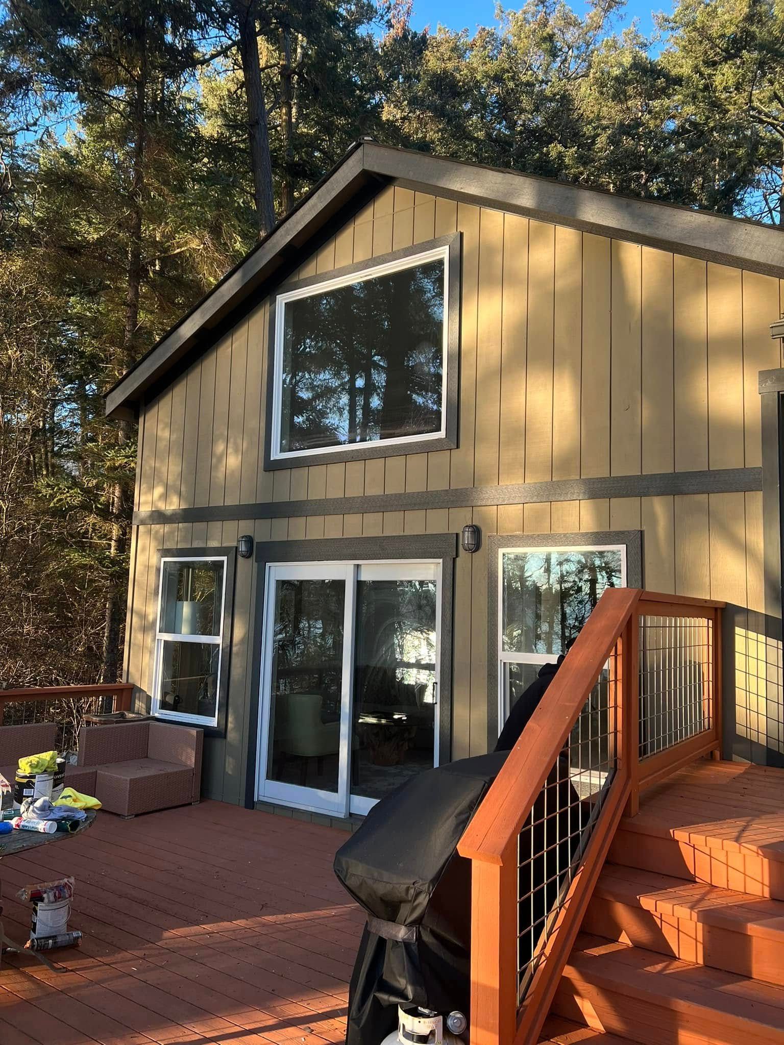 Cabin with brown siding and deck, surrounded by trees.