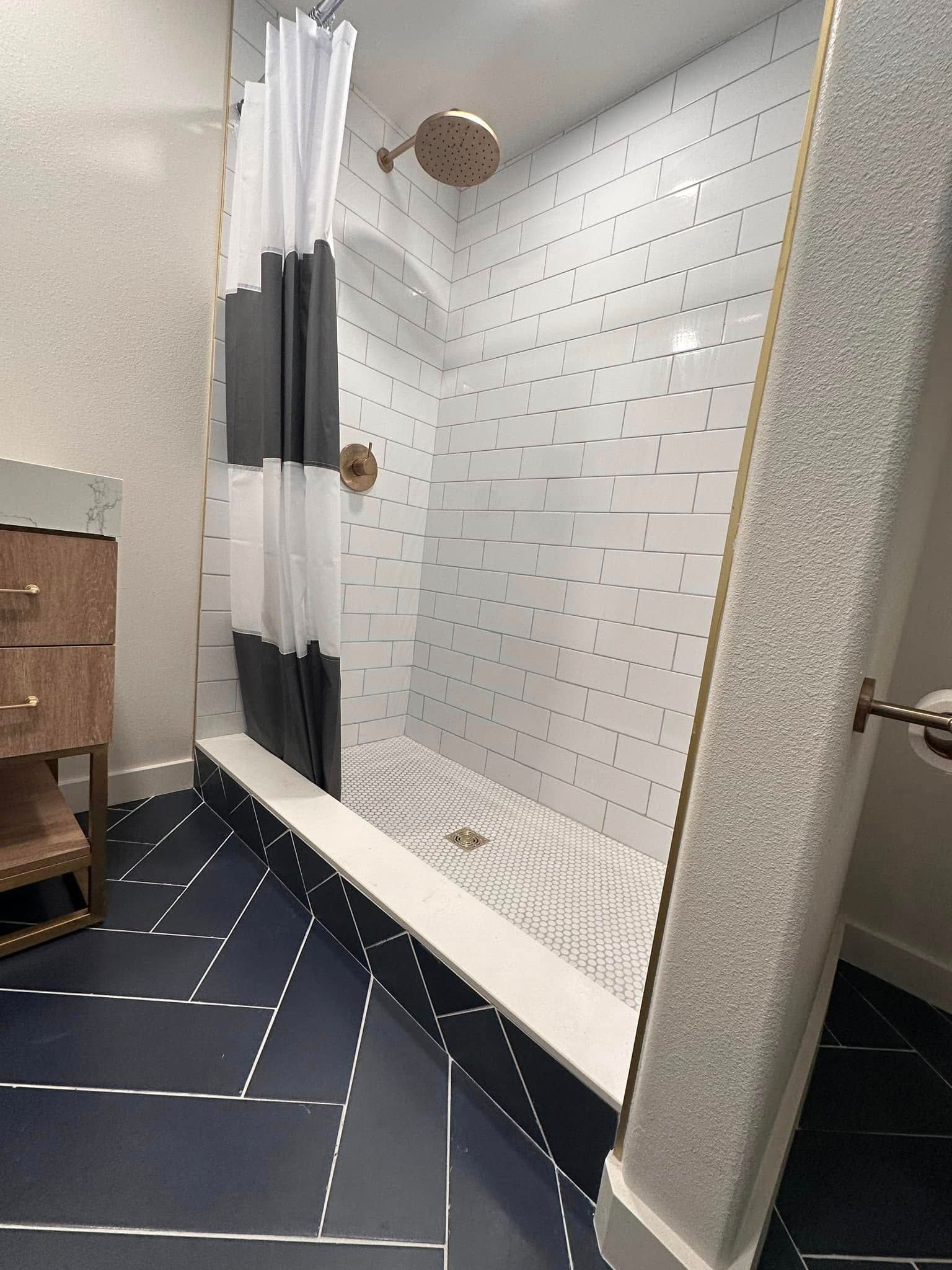 A modern bathroom with a shower featuring white tile and a black and white shower curtain.
