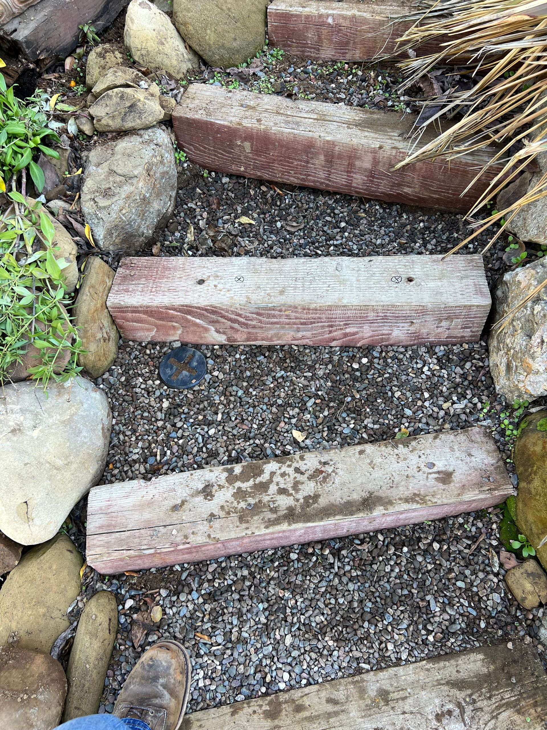 A Person Is Standing On A Set Of Wooden Steps Surrounded By Rocks - Oxnard, CA - 4J's Plumbing And Drain Cleaning