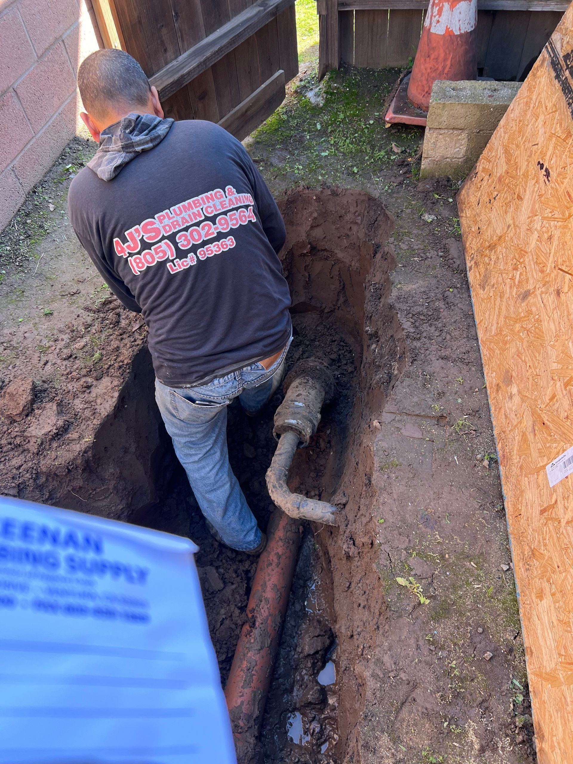 A Man In A Black Shirt Is Working On A Pipe In The Dirt - Oxnard, CA – 4J's Plumbing And Drain Cleaning