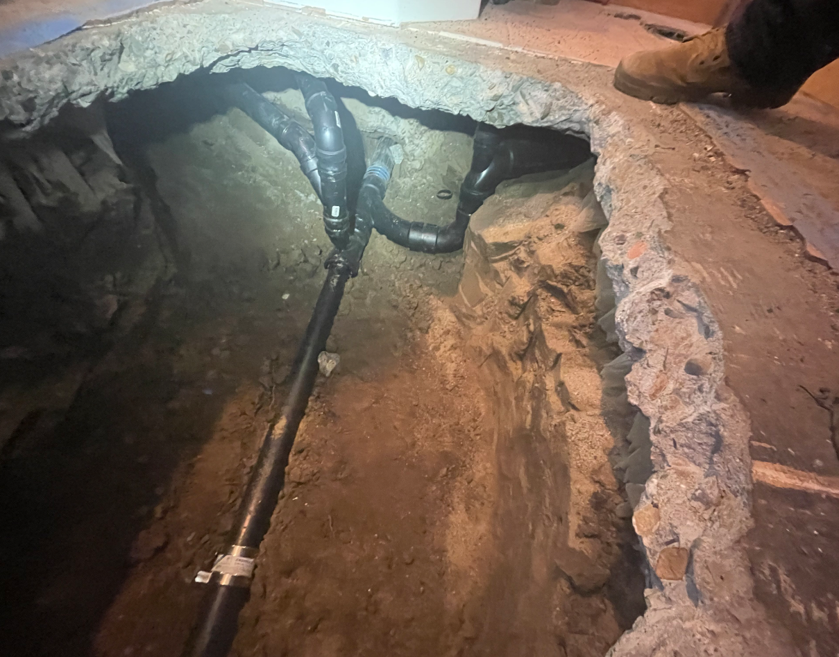 A Person Is Standing In A Hole In The Ground With Pipes Coming Out Of It - Oxnard, CA – 4J's Plumbing And Drain Cleaning