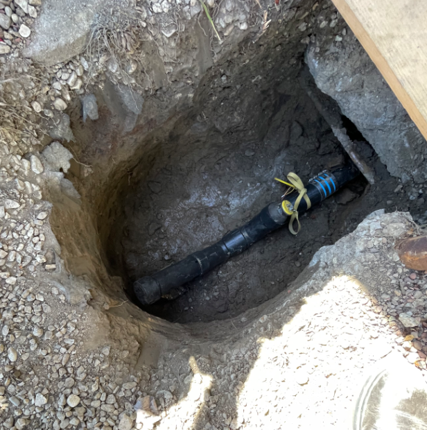 A Black Pipe Is Laying In A Hole In The Ground - Oxnard, CA – 4J's Plumbing And Drain Cleaning