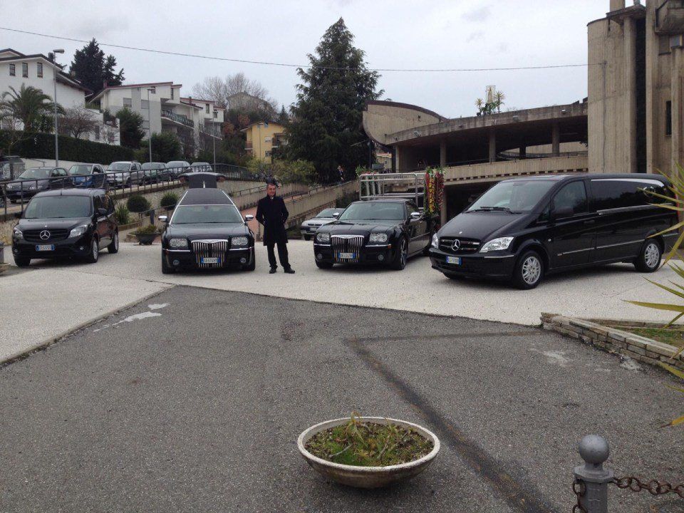 Un uomo è in piedi davanti a una fila di auto nere