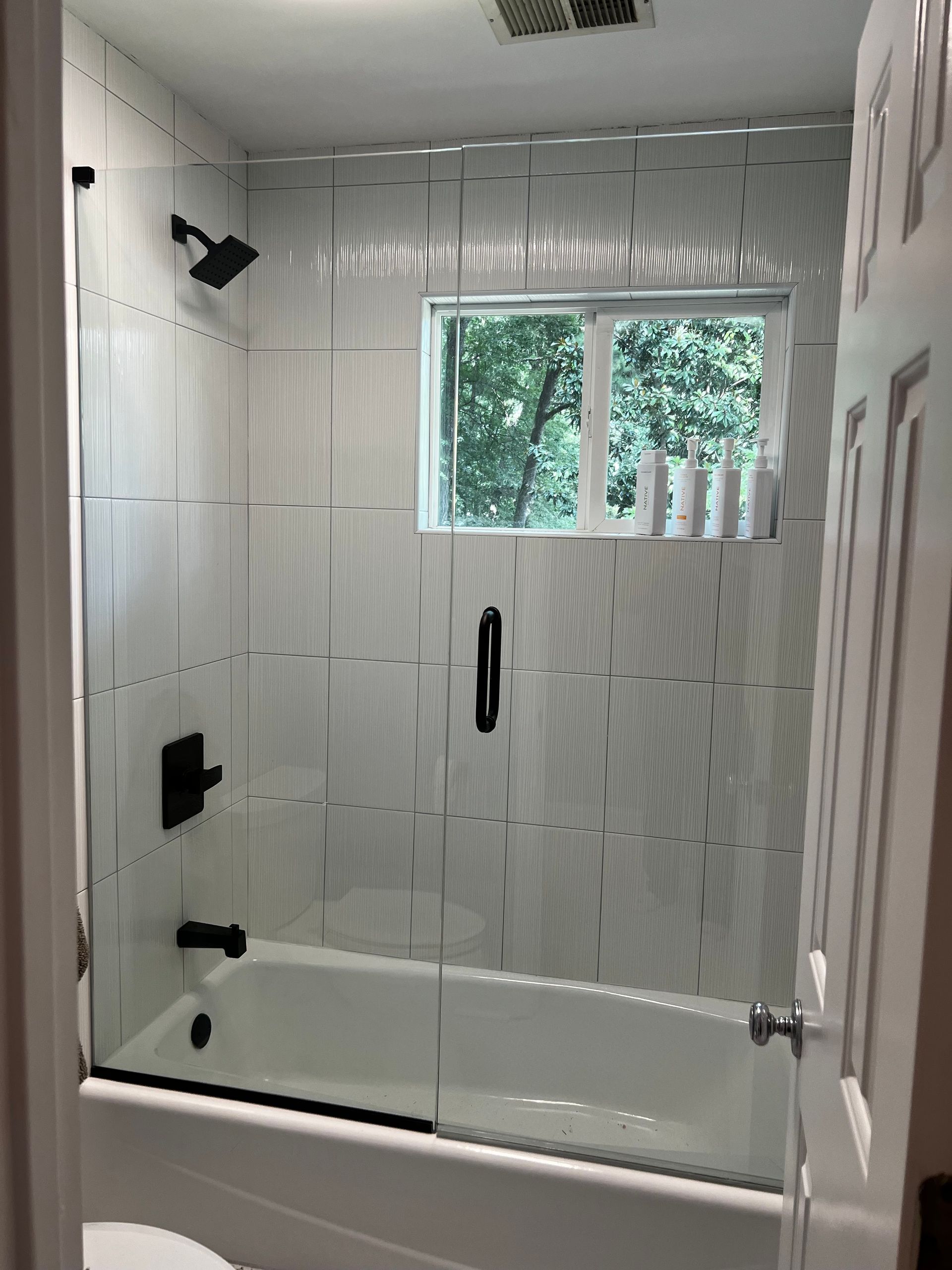 A bathroom with a bathtub and a shower with a glass door.