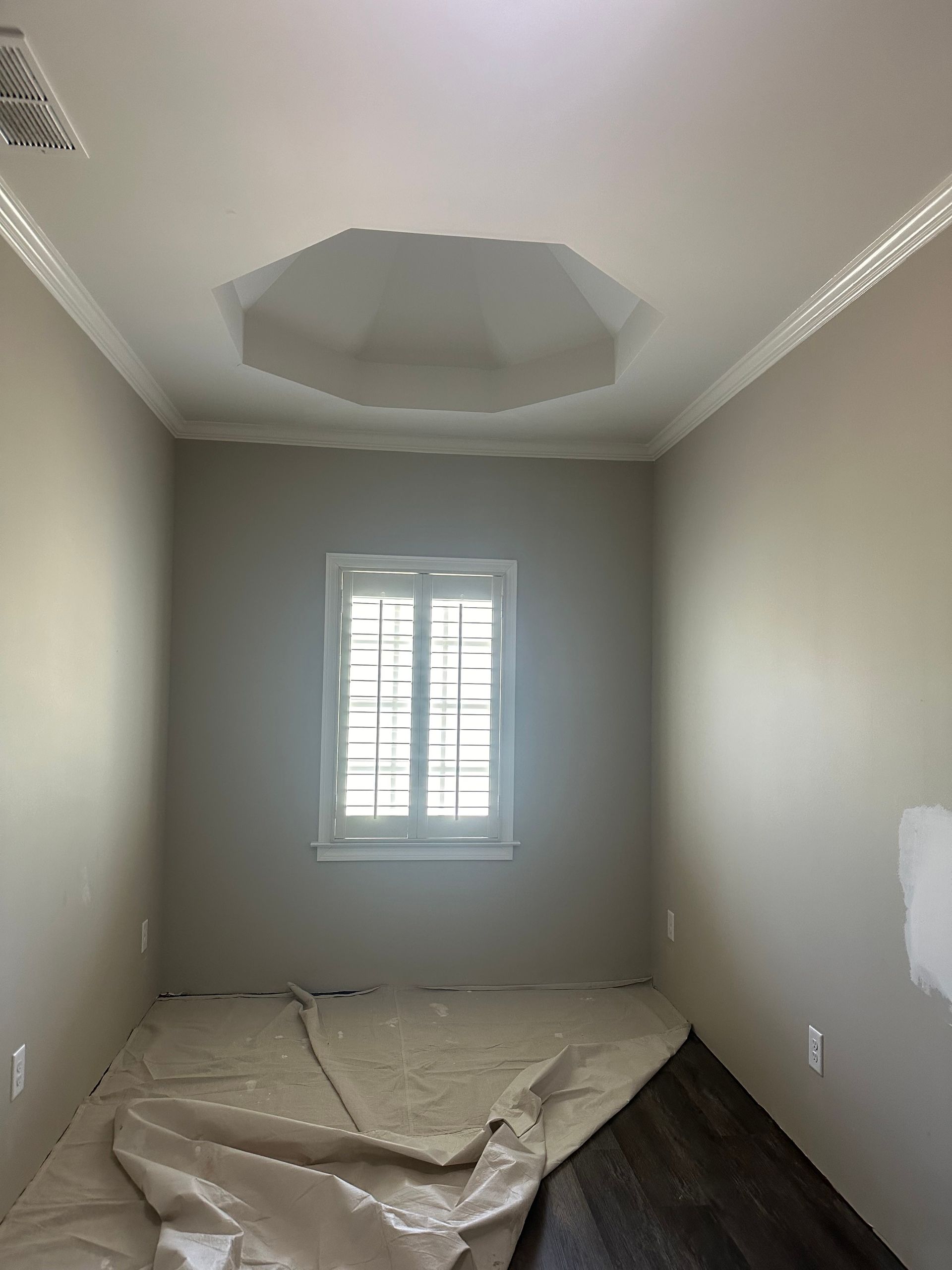 An empty room with a window and a ceiling fan.