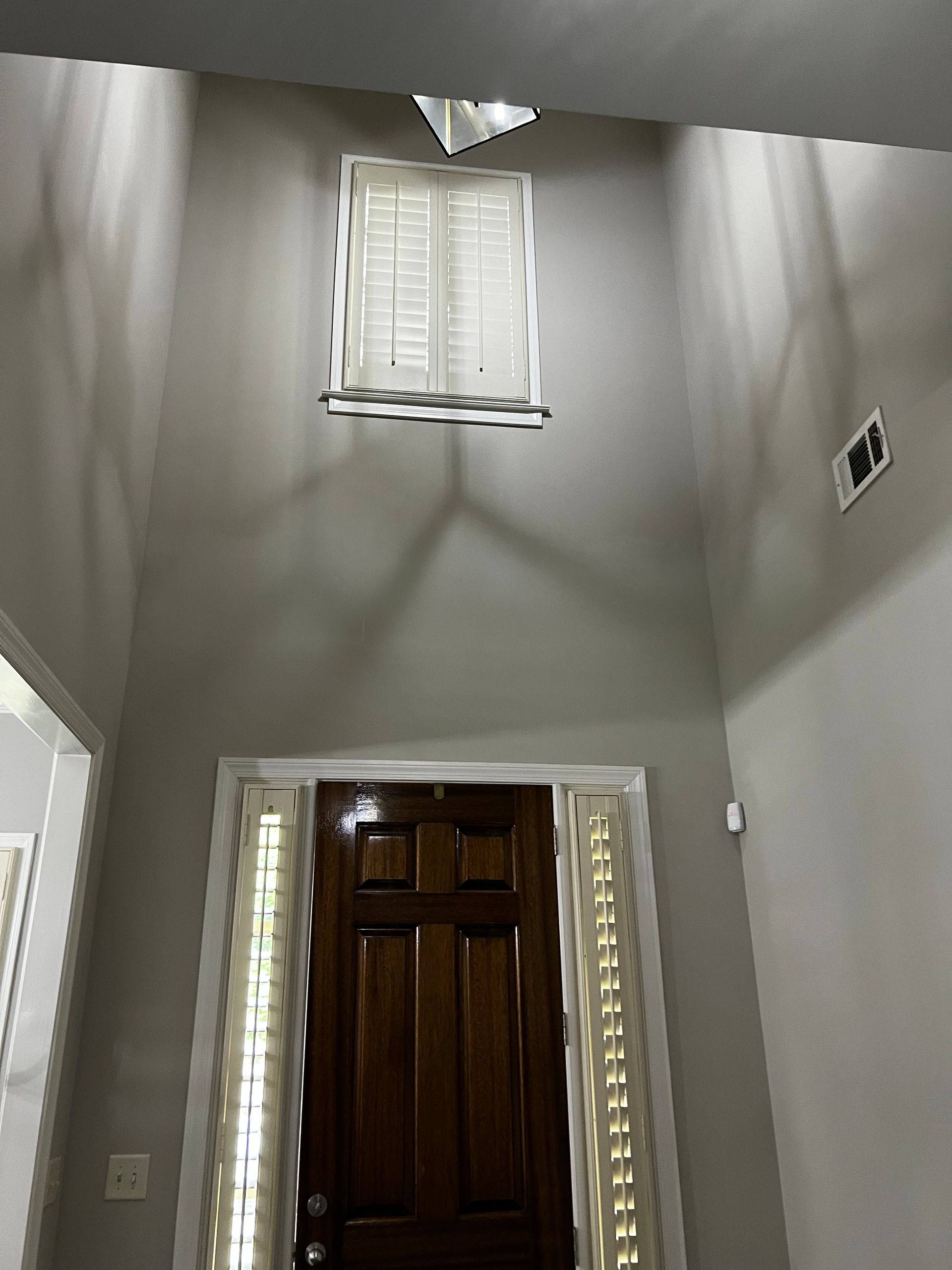 A hallway with a wooden door and a light hanging from the ceiling.