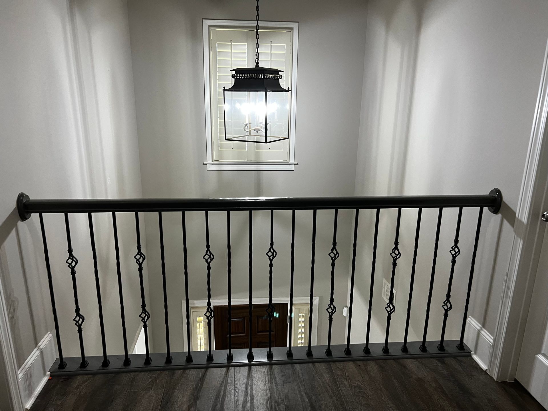 A staircase with a wrought iron railing and a lantern hanging from the ceiling.