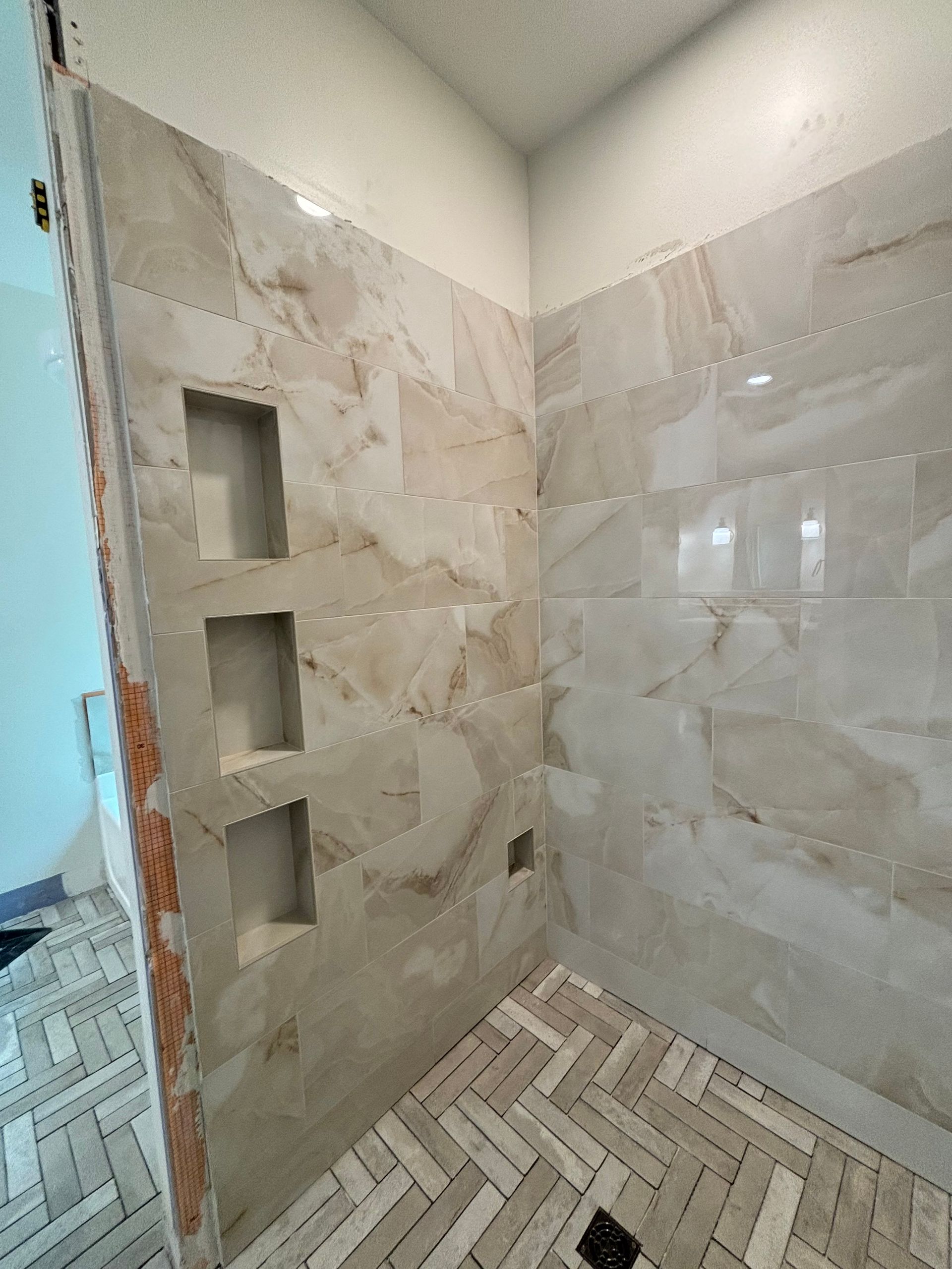 A bathroom with a walk in shower and a marble wall.