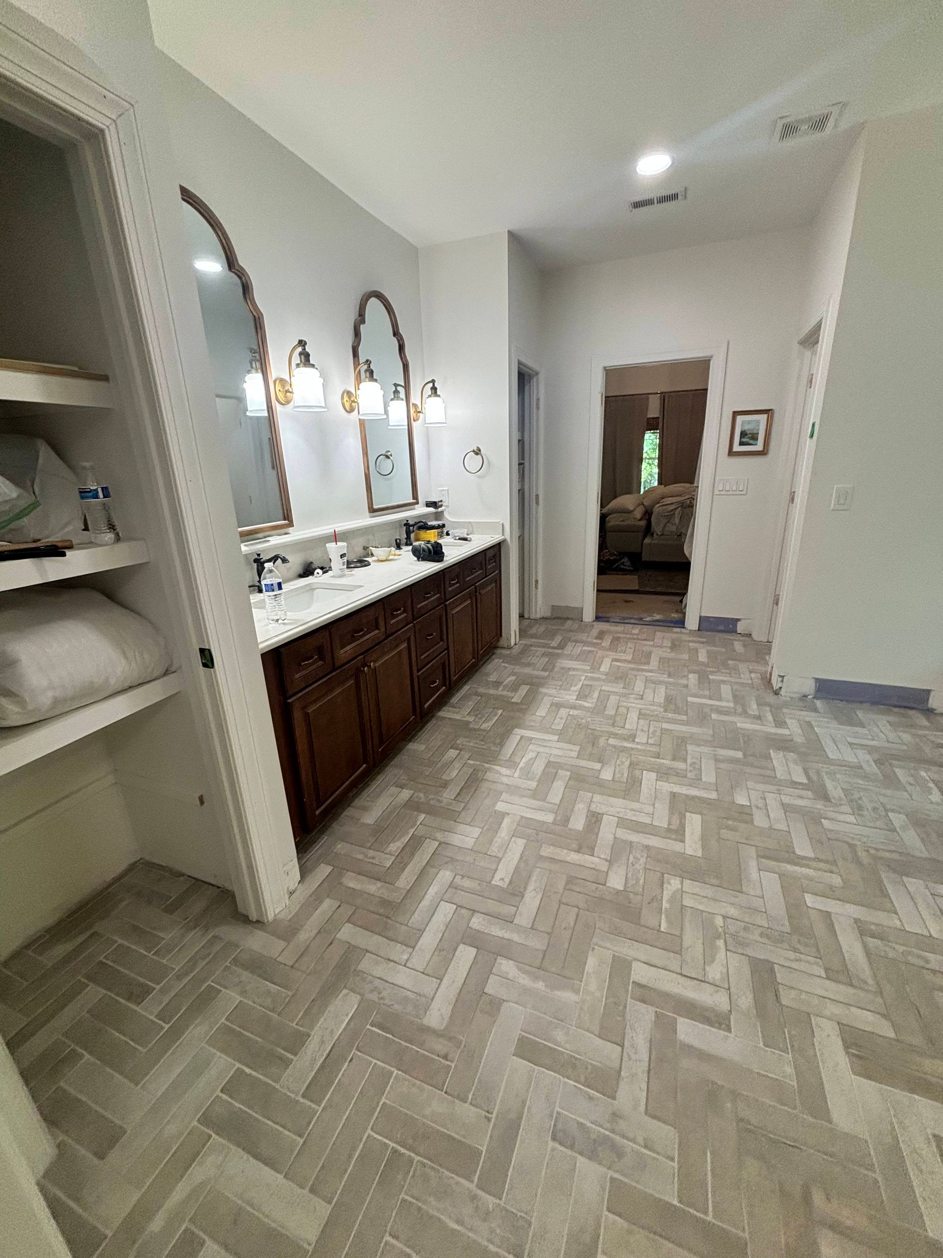 A bathroom with two sinks , two mirrors and a herringbone floor.