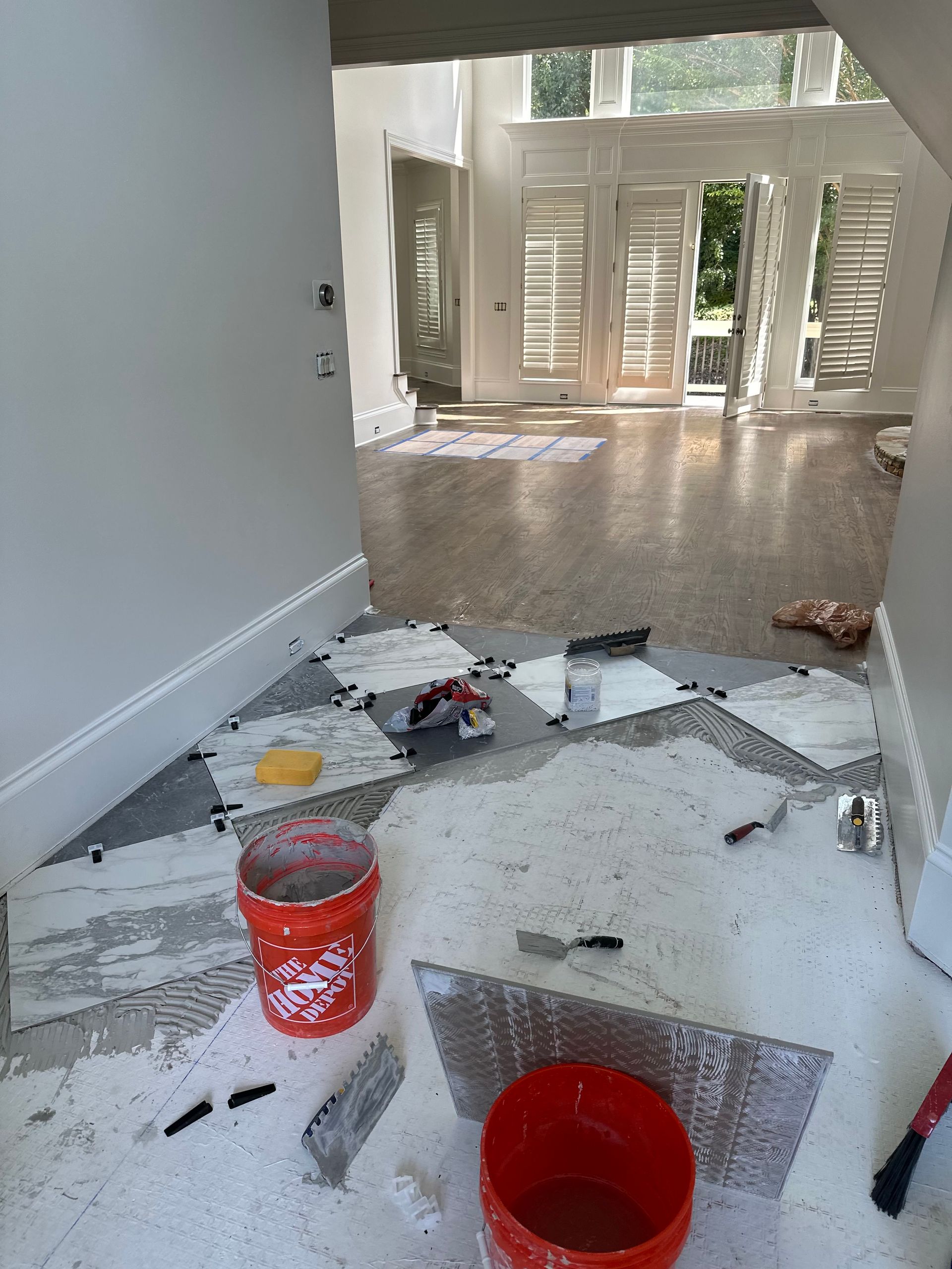 A room with a bucket of paint and a spatula on the floor.