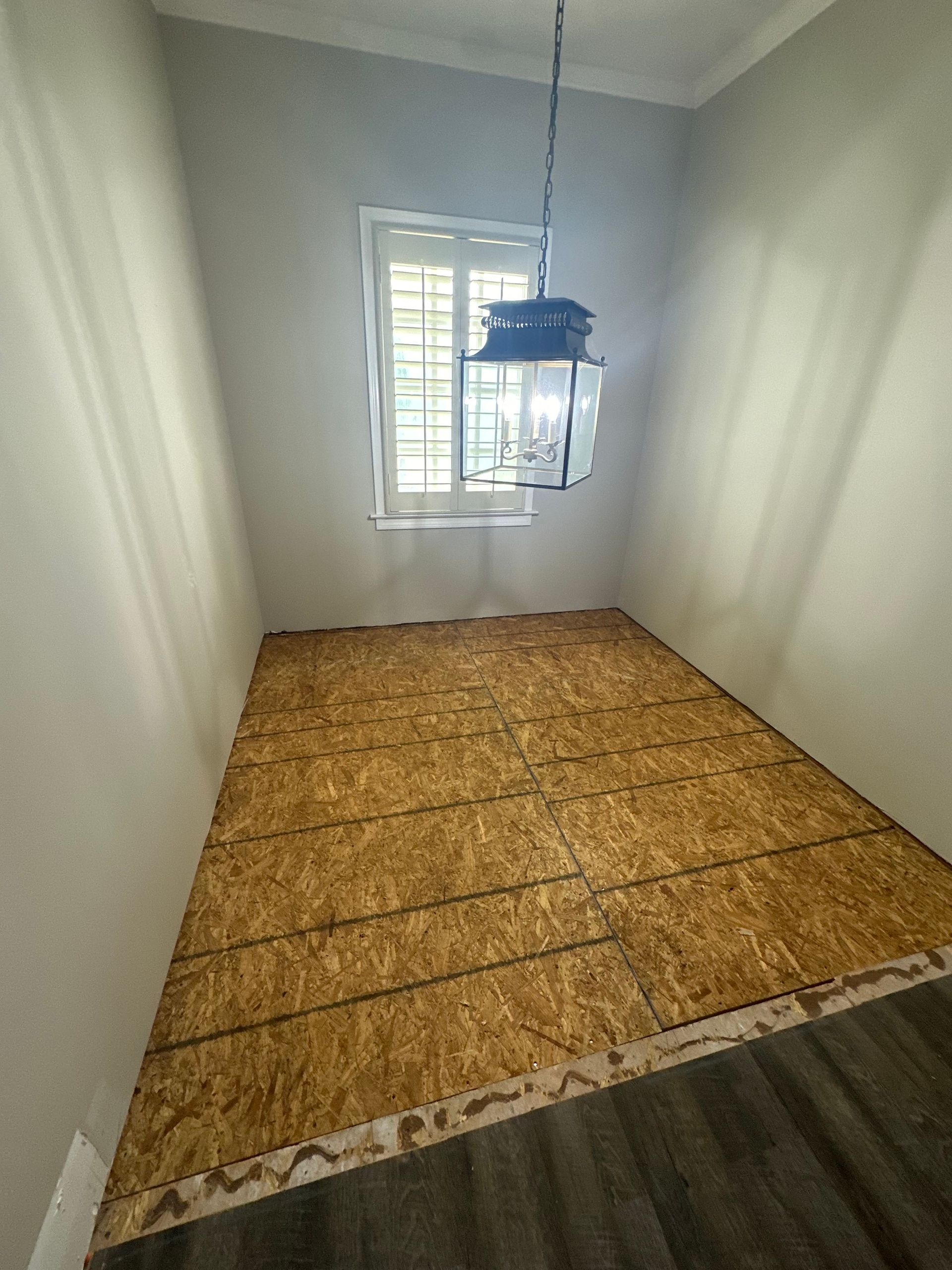 A room with a wooden floor and a chandelier hanging from the ceiling.