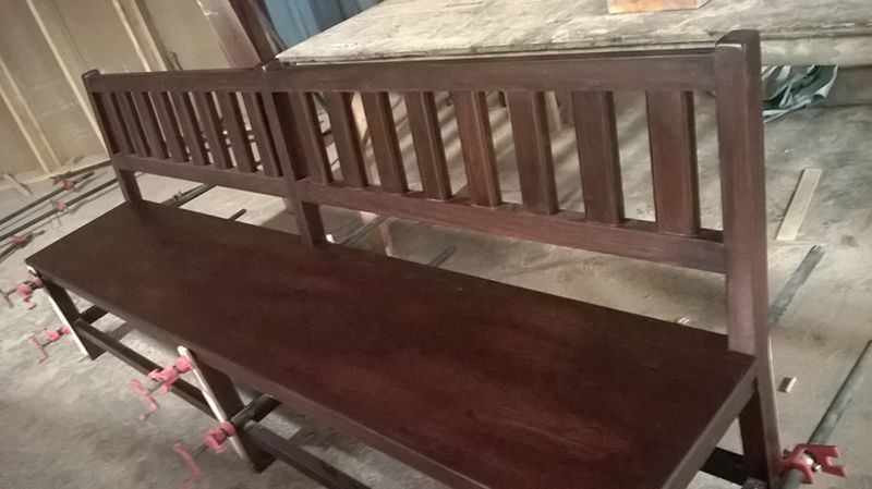 A Wooden Bench With A Striped Back Is Sitting On A Cement Floor