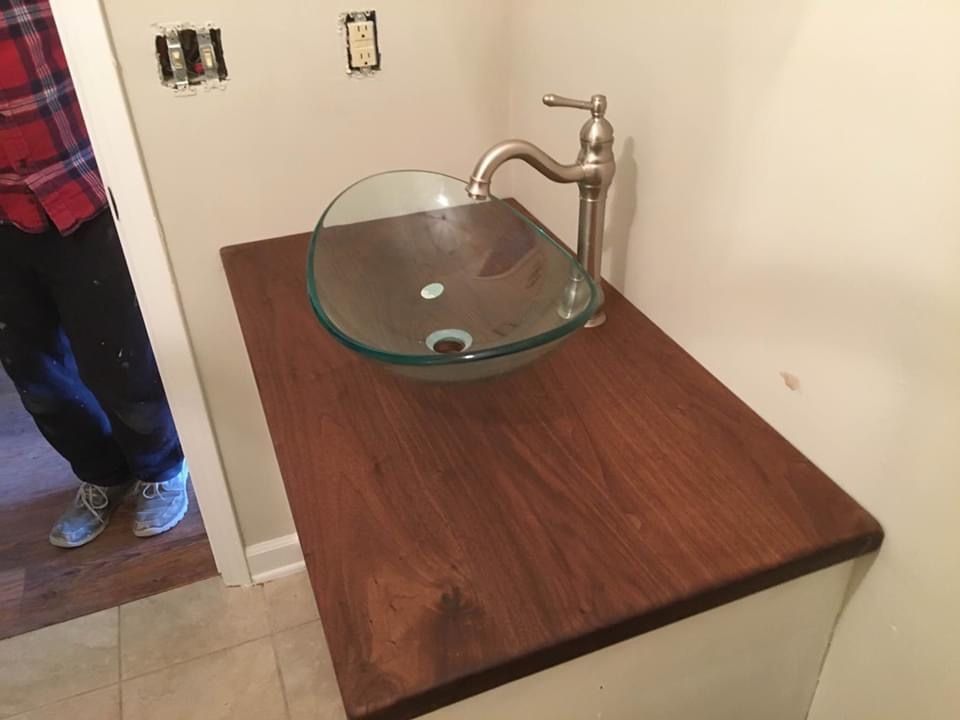 A Bathroom Sink With A Glass Bowl On A Wooden Counter Top