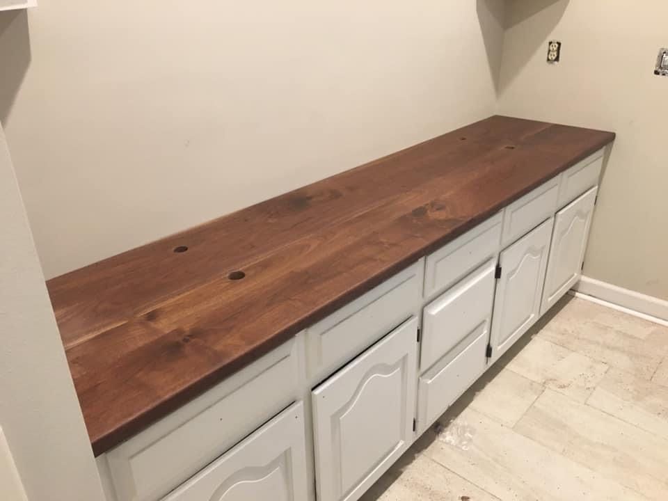 A Kitchen With White Cabinets And A Wooden Counter Top.