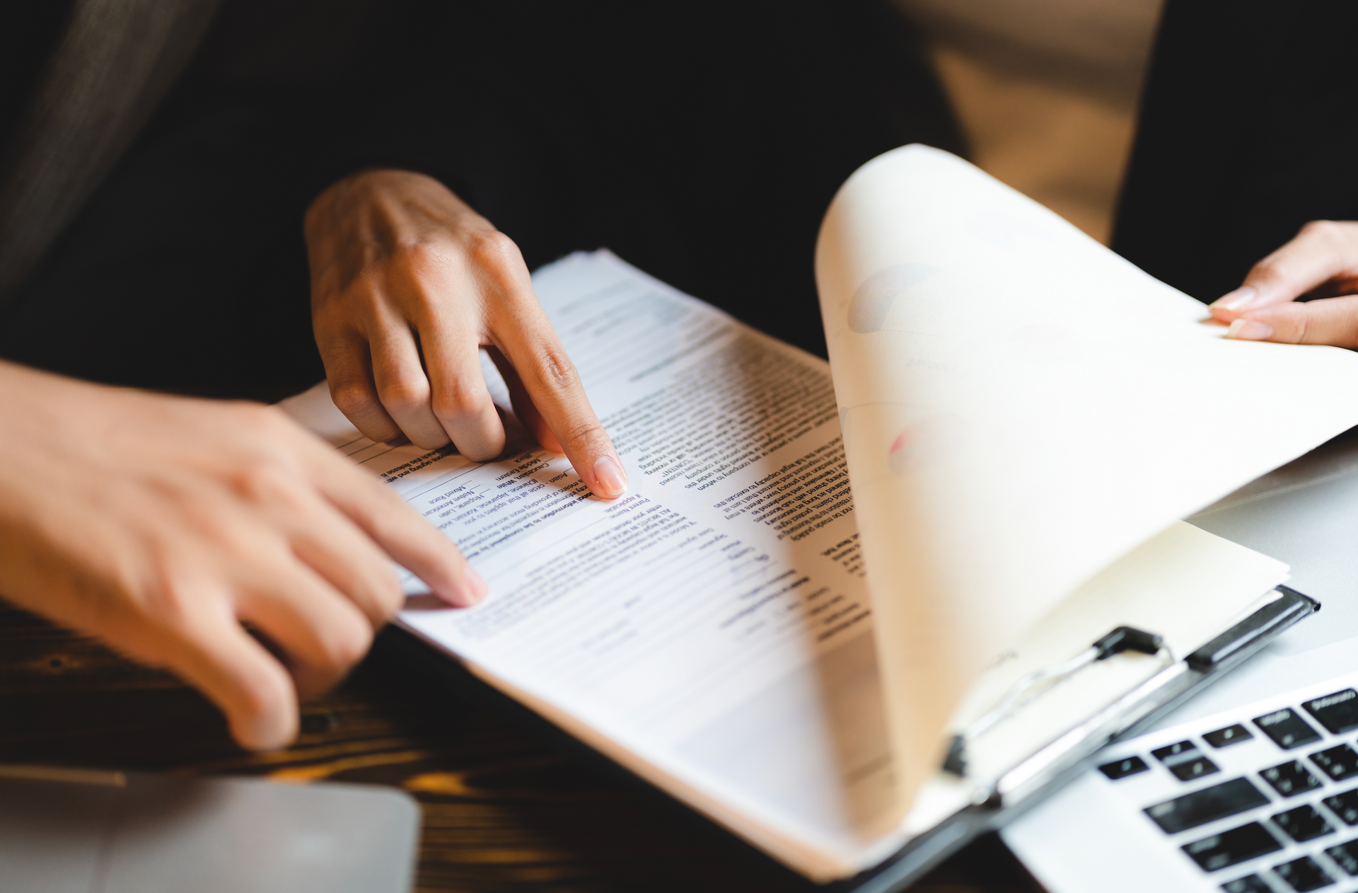 A person is pointing at a piece of paper on a table.