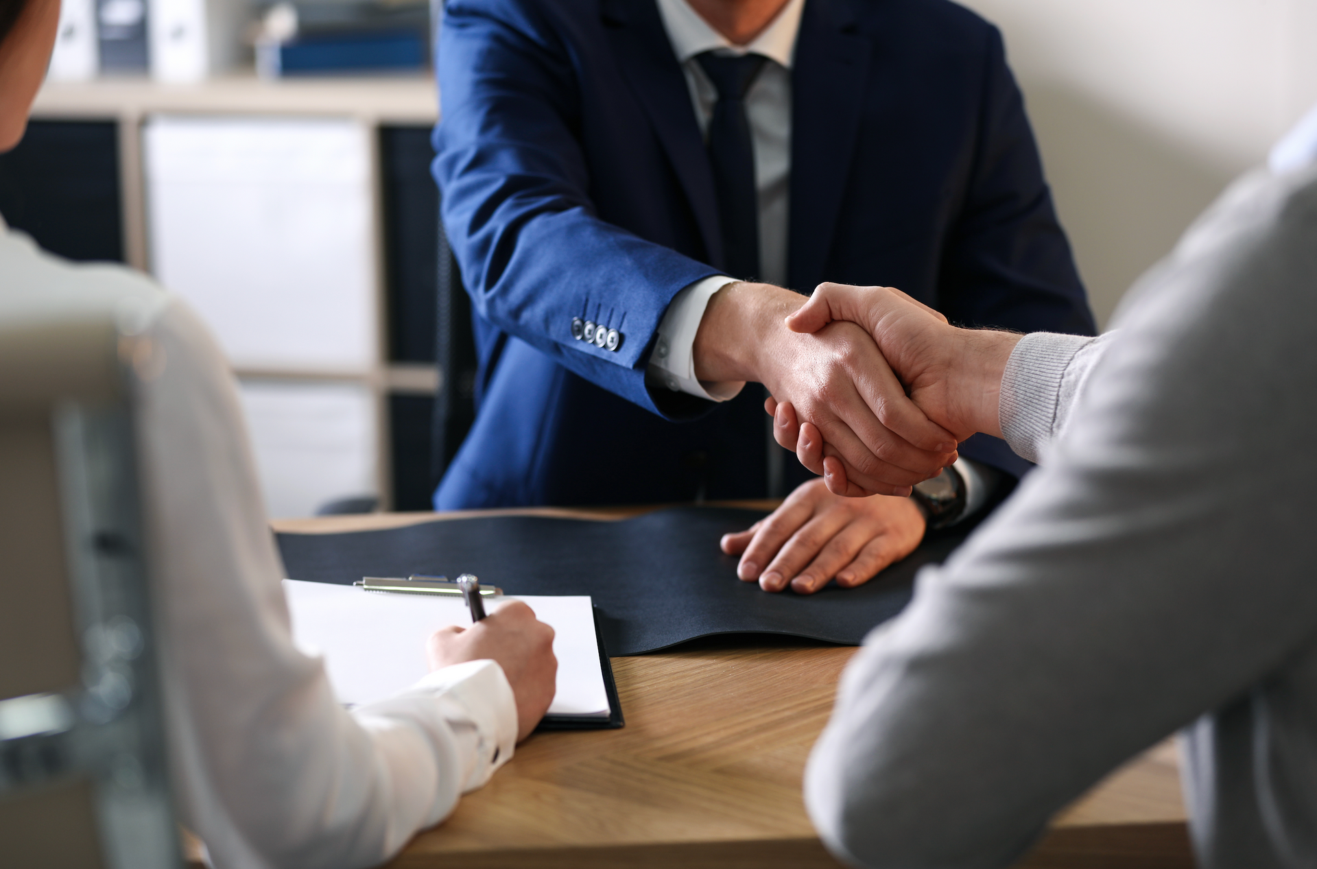 A man in a suit and tie is shaking hands with a woman.