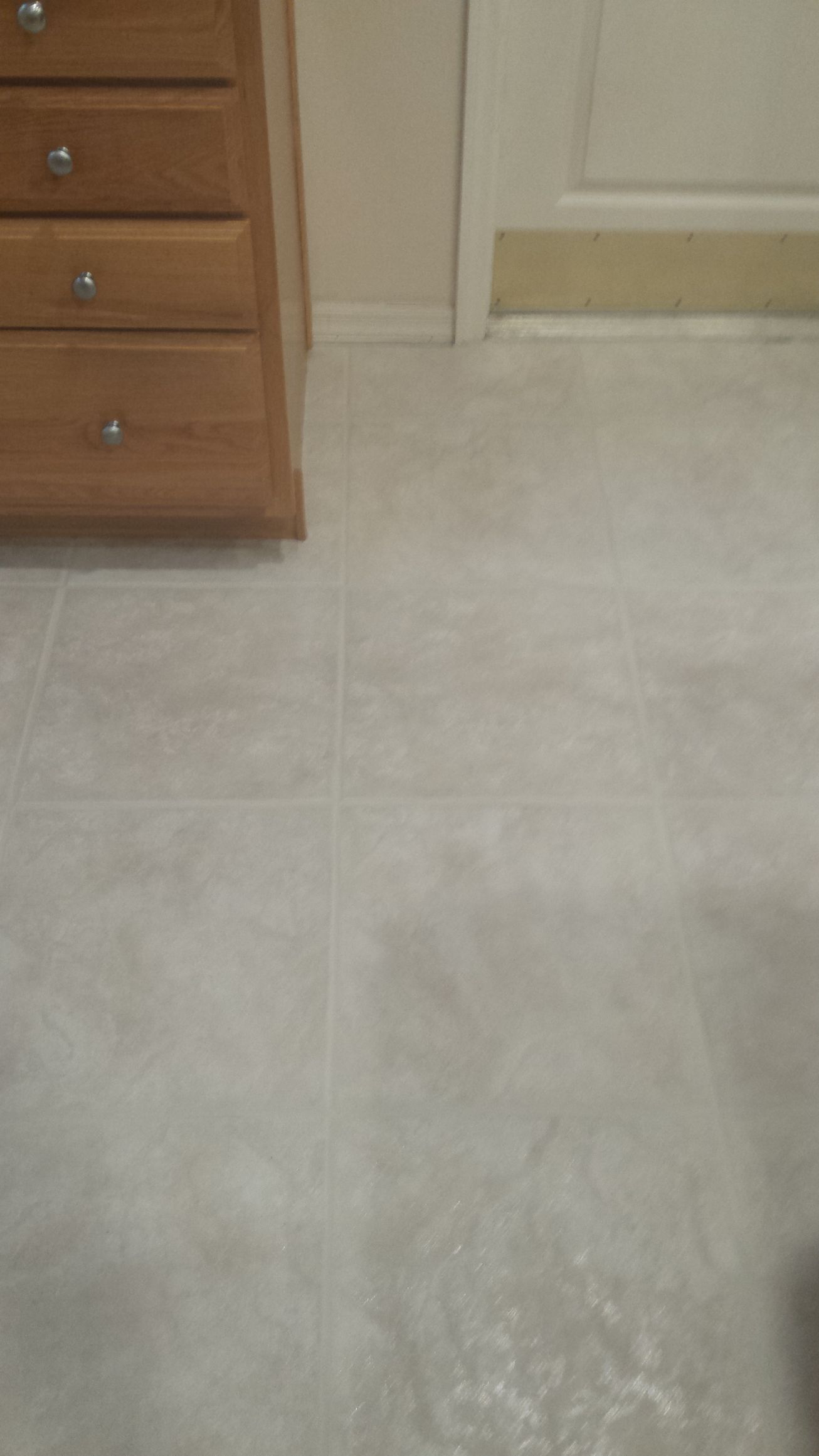 A white tile floor with a wooden dresser in the background.