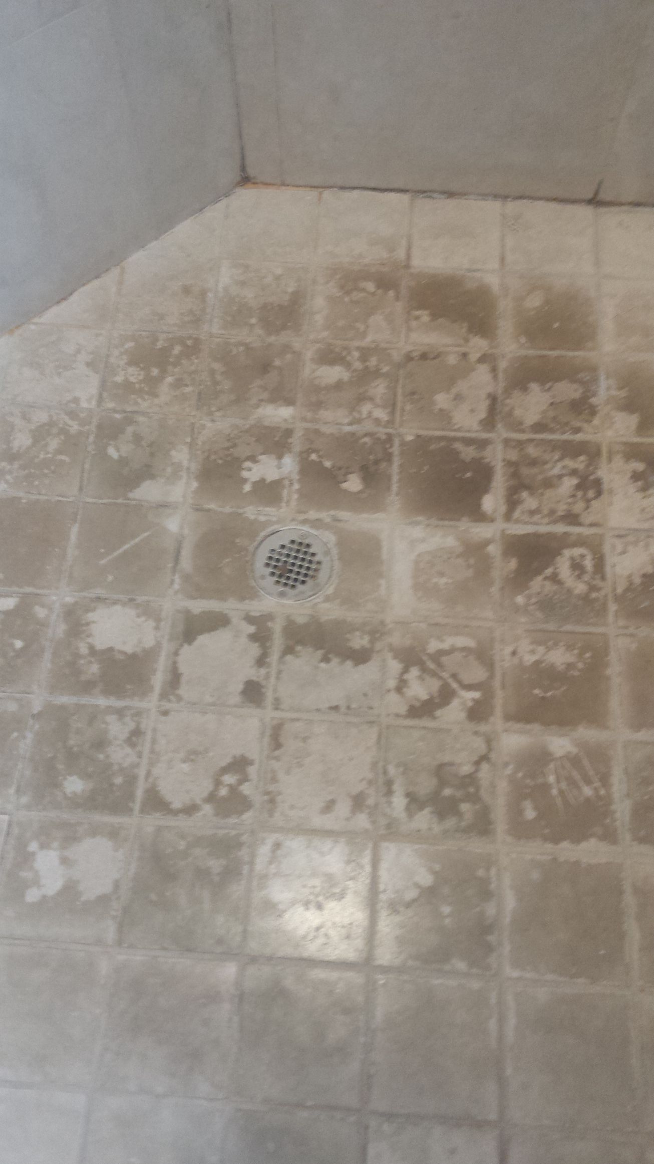 A close up of a tiled floor in a bathroom with a drain.