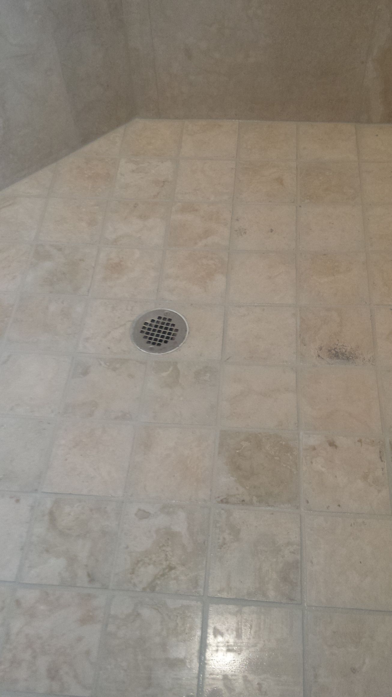 A shower stall with a drain on the floor.