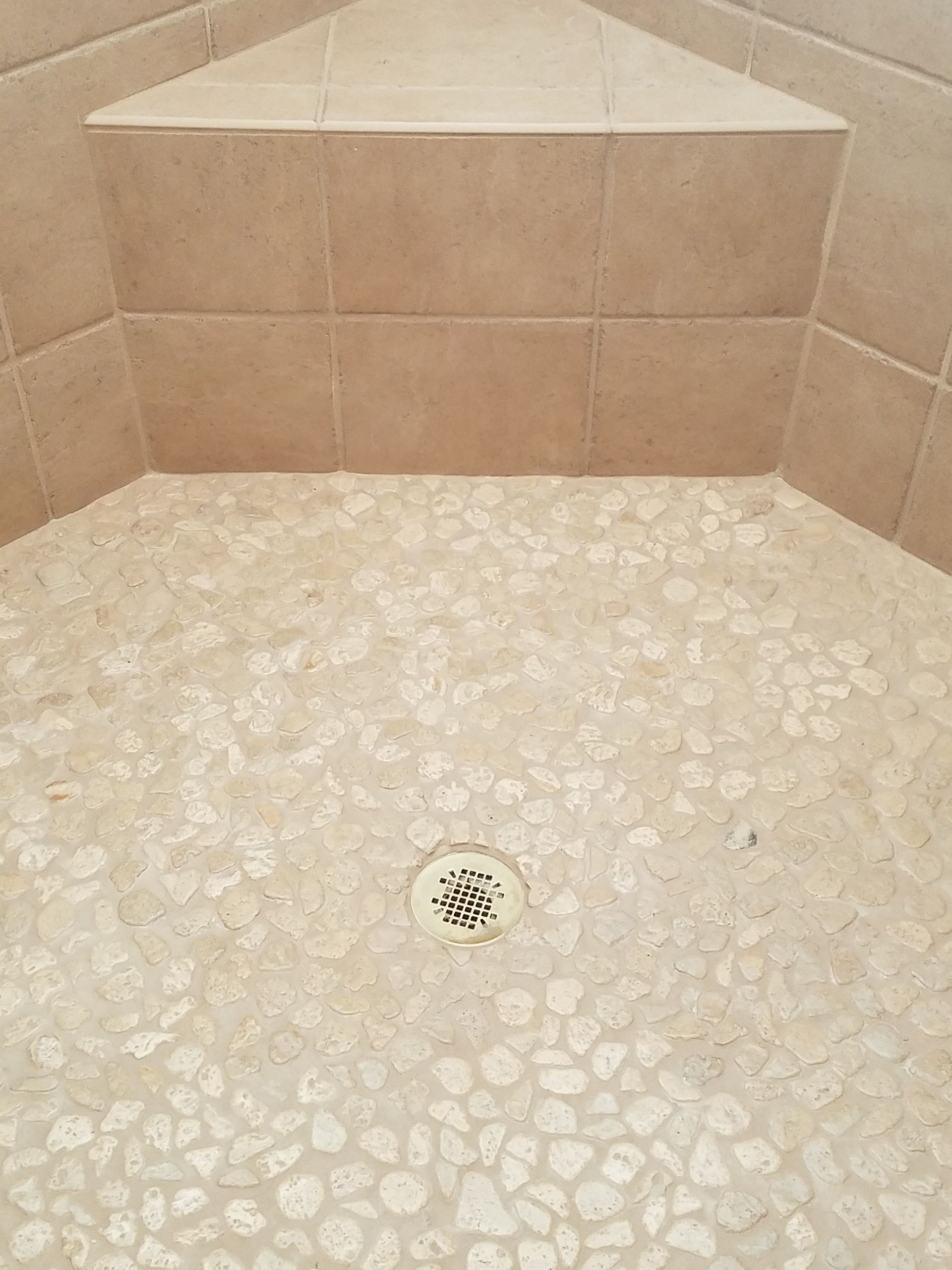 A close up of a shower floor with a drain.