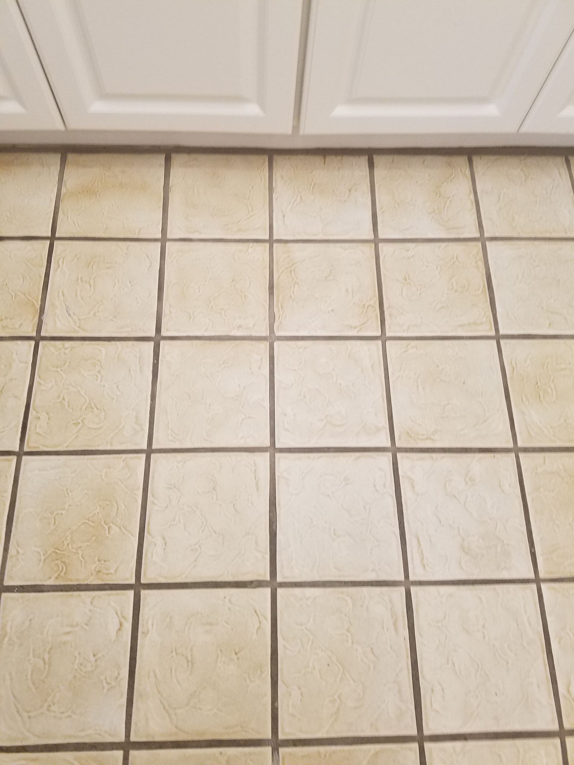 A close up of a tiled floor next to a cabinet.