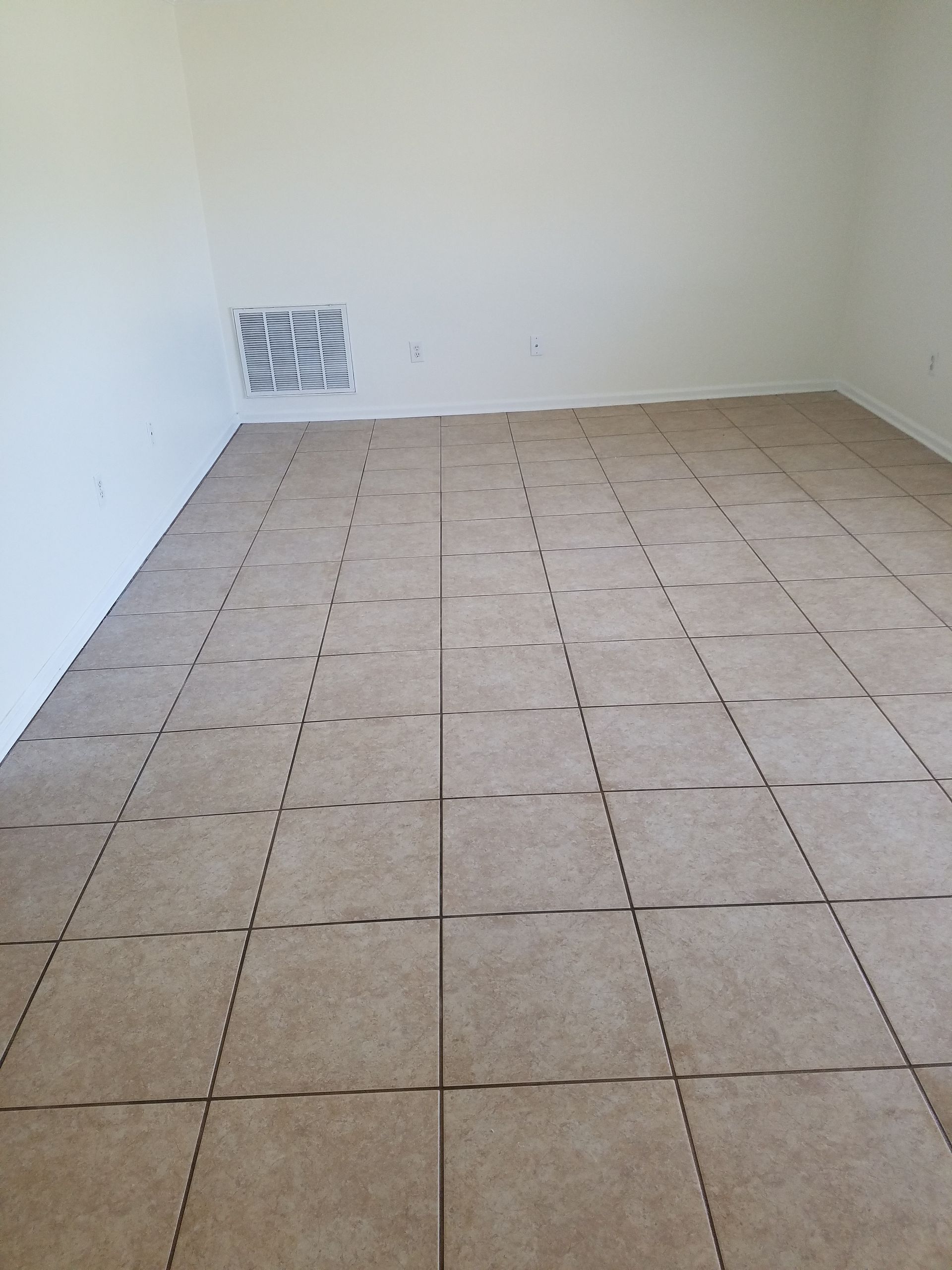 An empty room with a tiled floor and white walls.