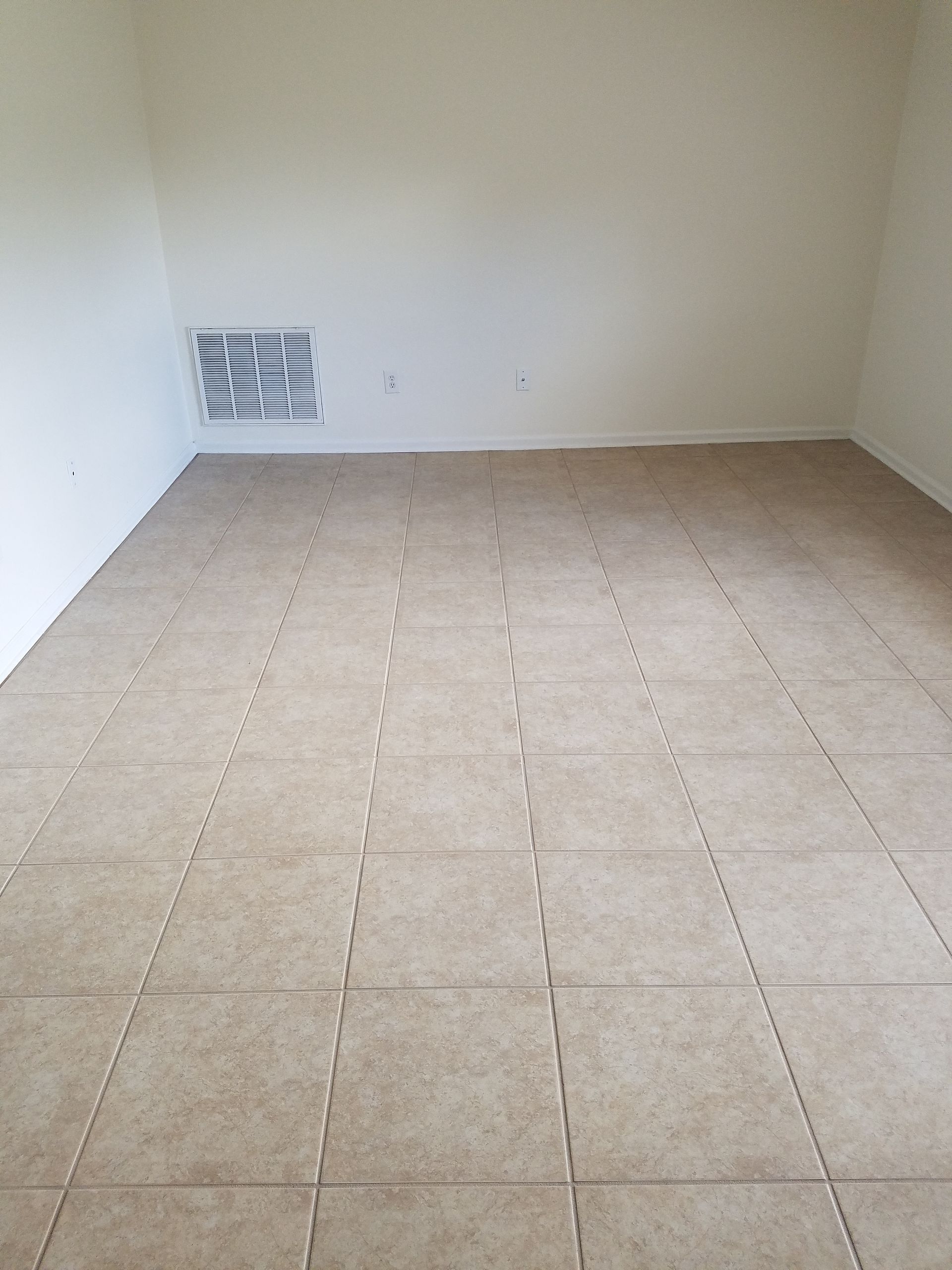 An empty room with a tiled floor and white walls.