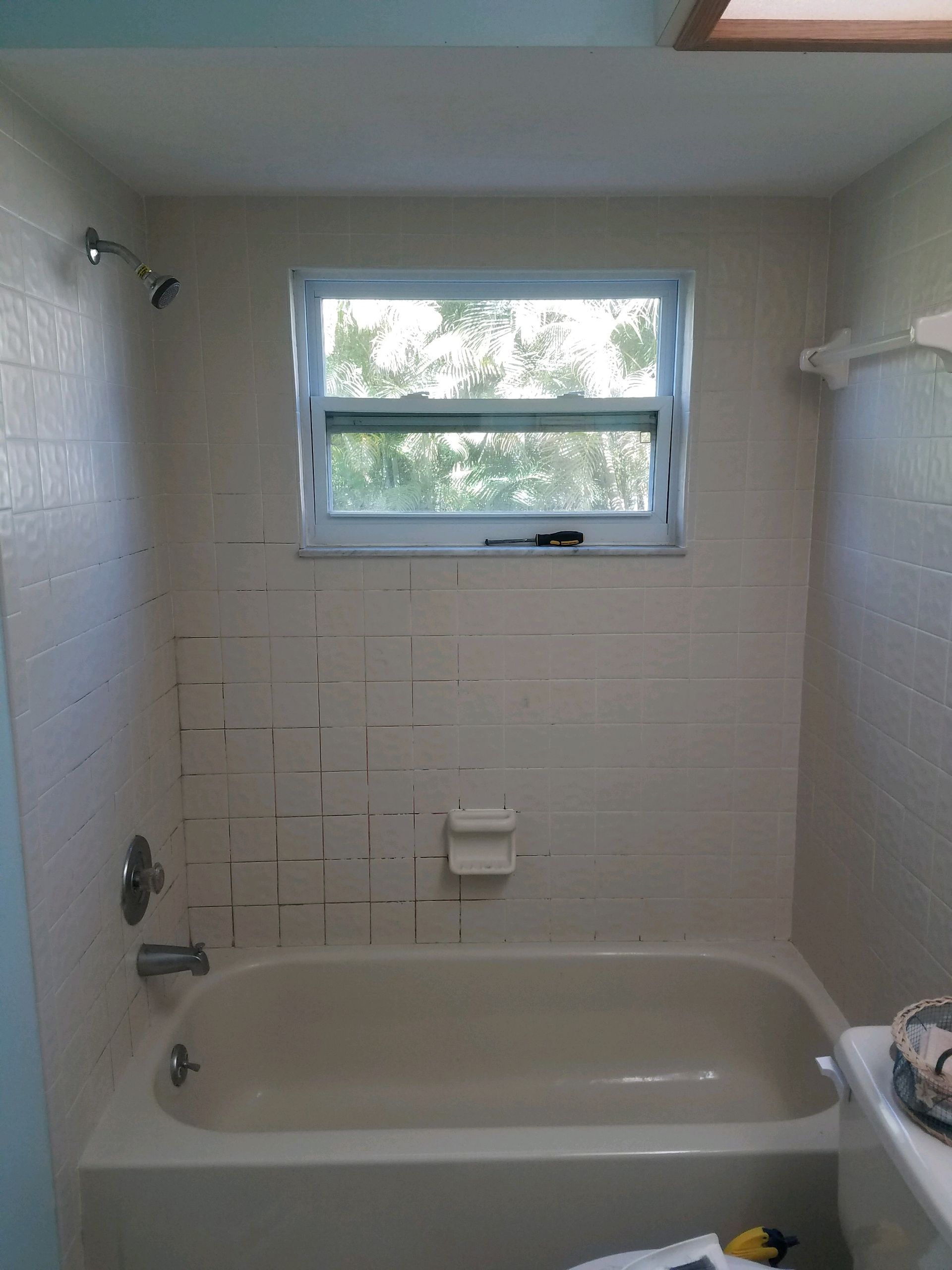 A bathroom with a bathtub , toilet , shower and window.