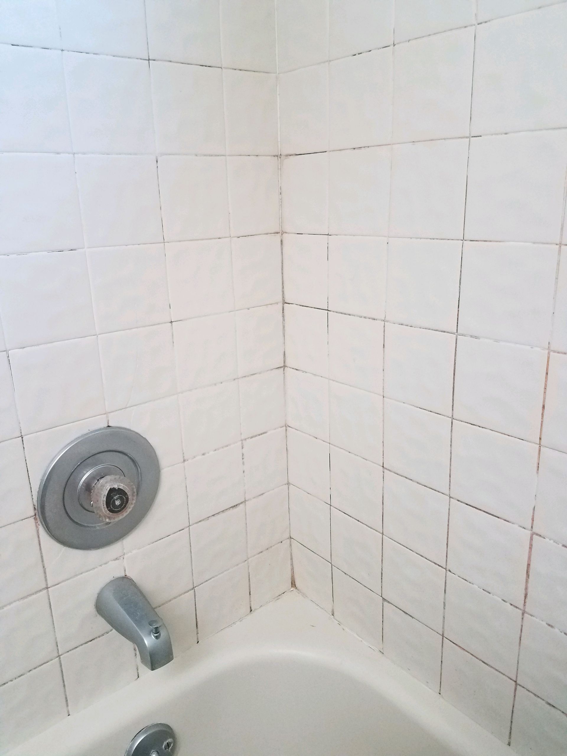 A bathtub in the corner of a bathroom with white tiles