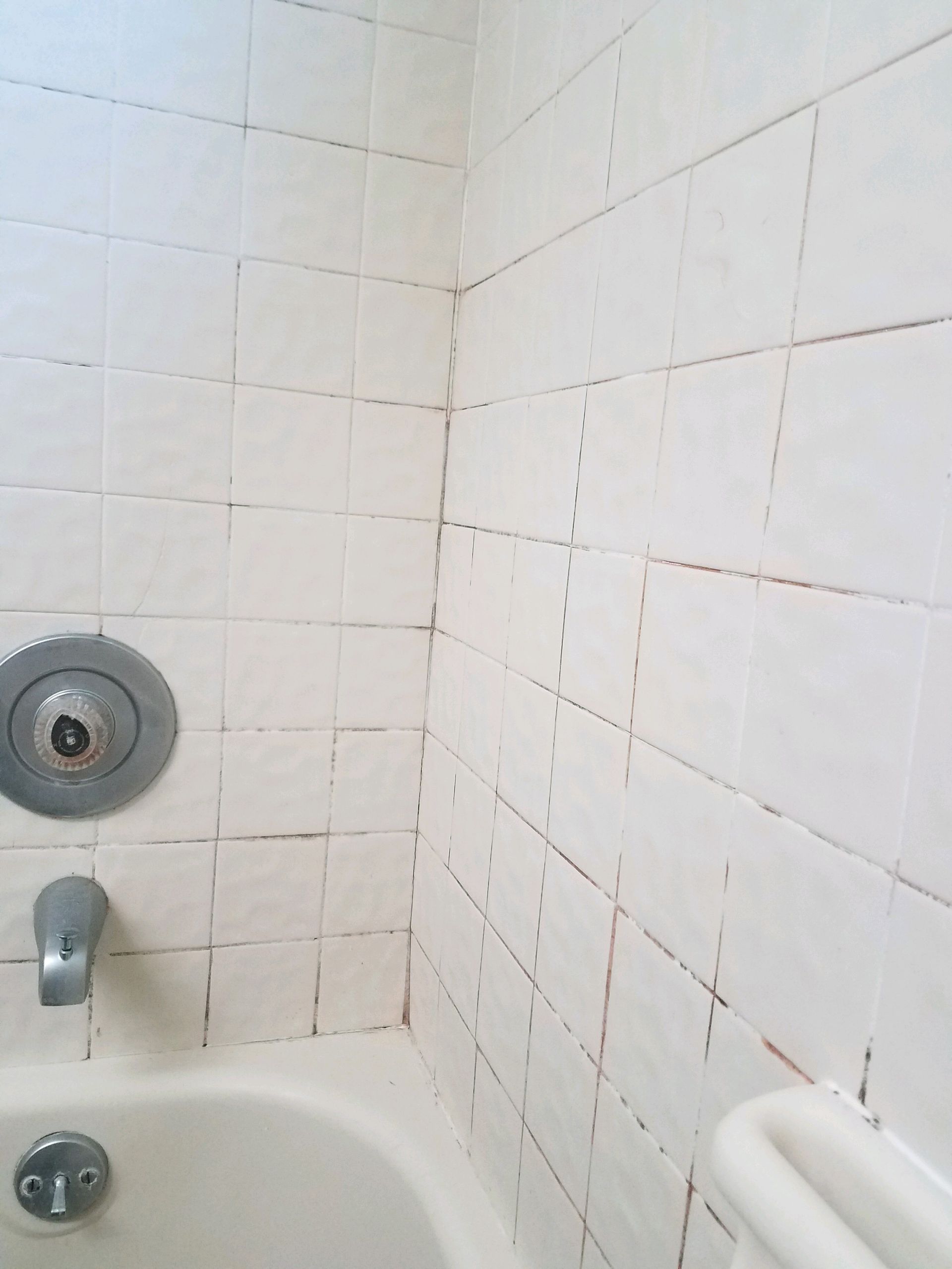 A bathroom with white tiles and a bathtub