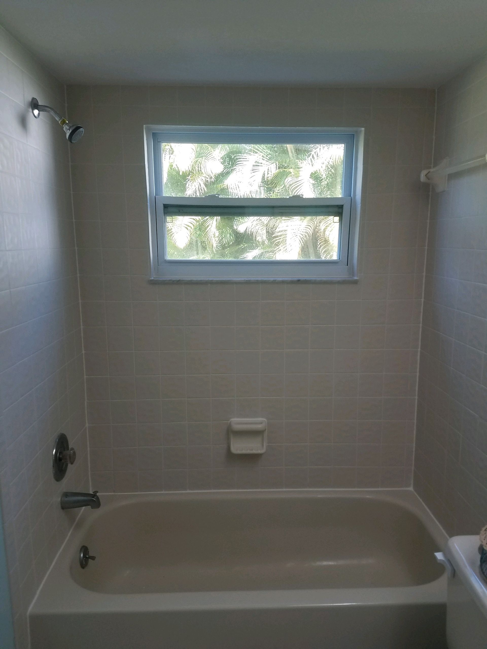 A bathroom with a bathtub , toilet , shower and window.