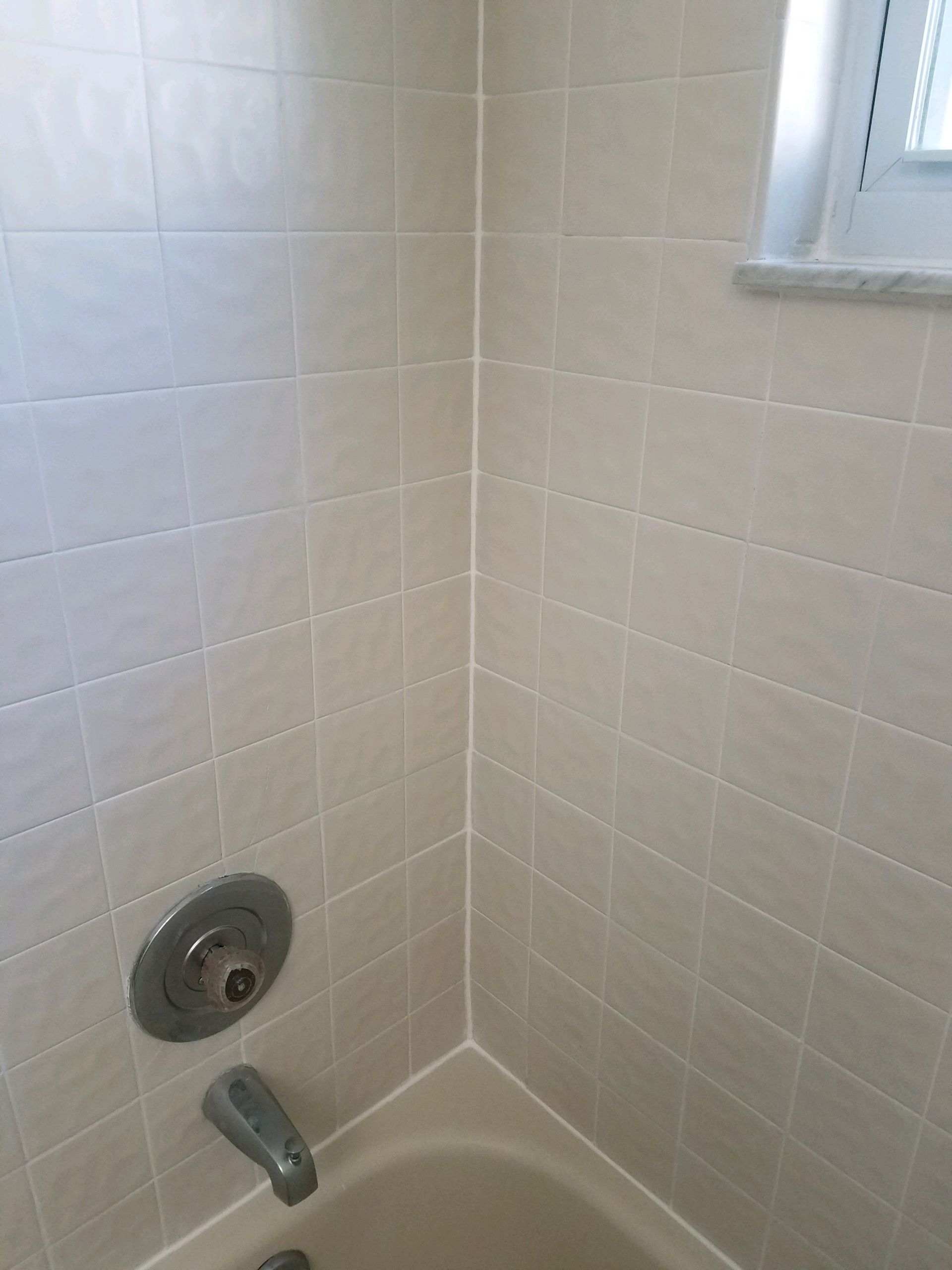 A bathroom with a bathtub , shower , and window.