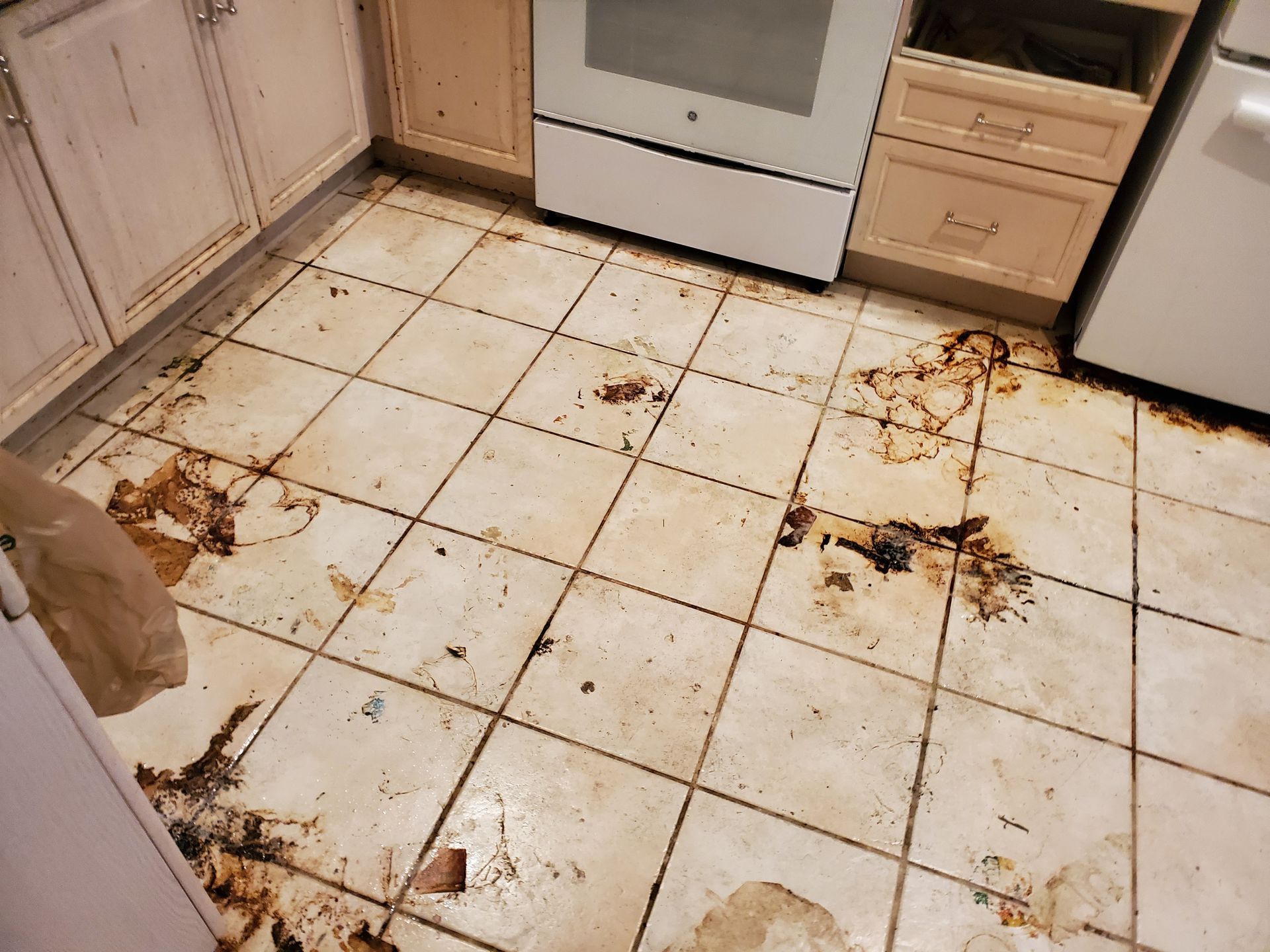 A kitchen with a dirty tile floor and a white stove.