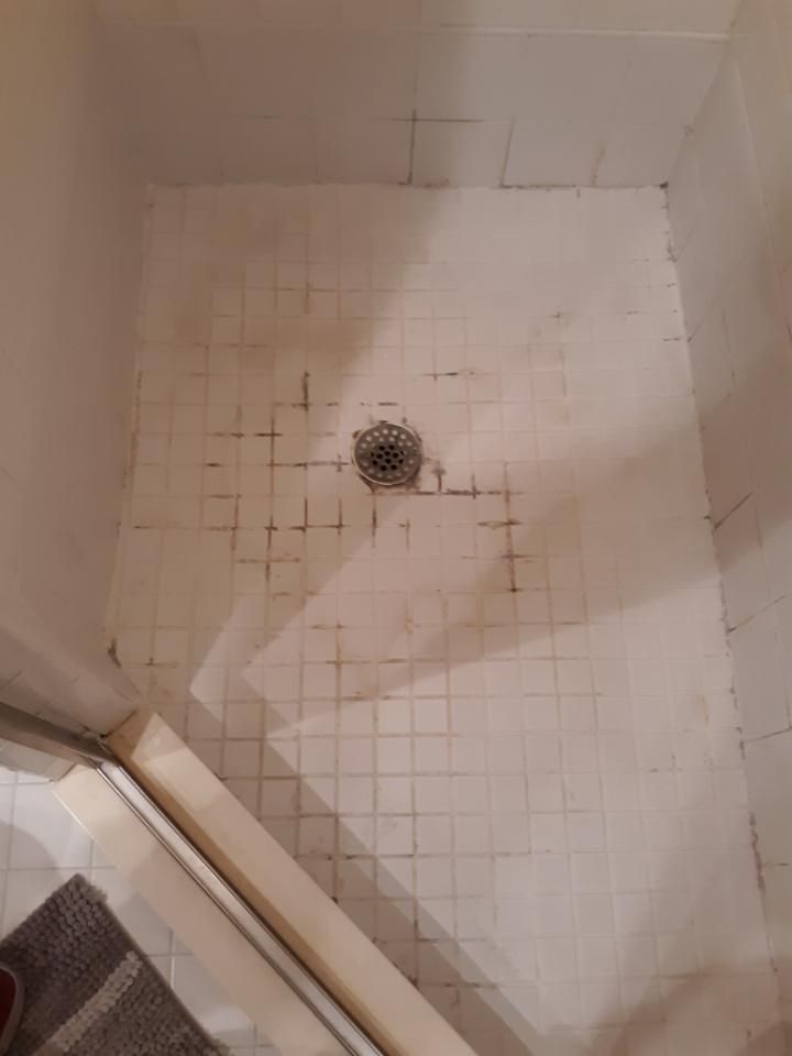 A shower stall with a drain in the middle of it.